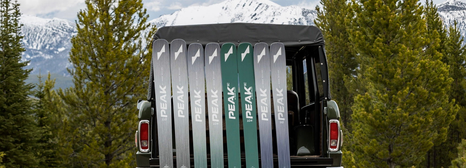 Peak Skis lined up leaning on a truck