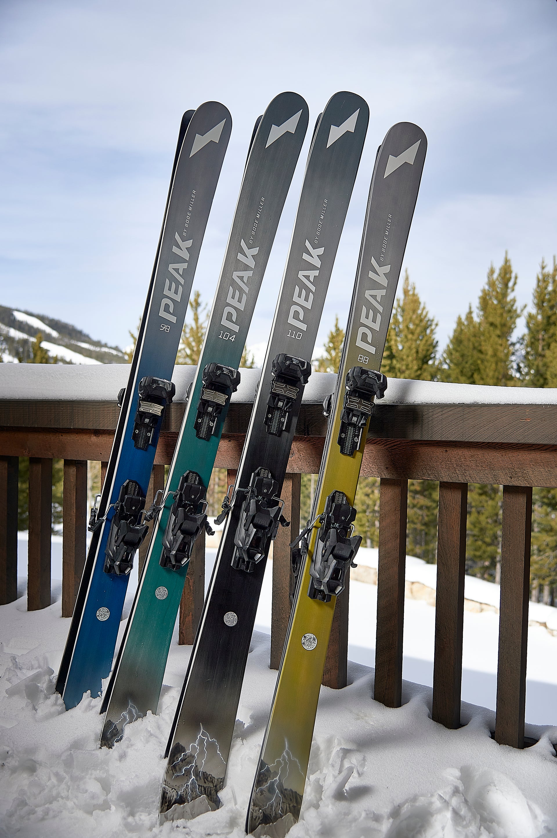 Peak Skis lined up leaning on a rail